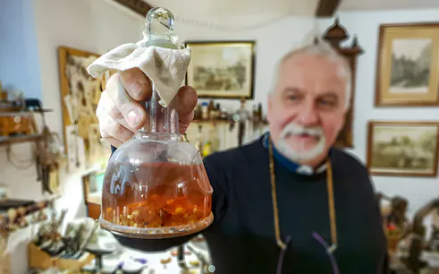 Man holding amber-filled flask at Gdańsk Amber Workshop.