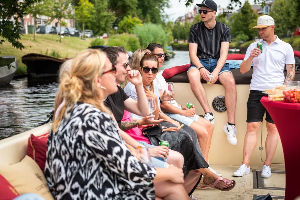 Group enjoying Harlem canal cruise on open boat with drinks and snacks.