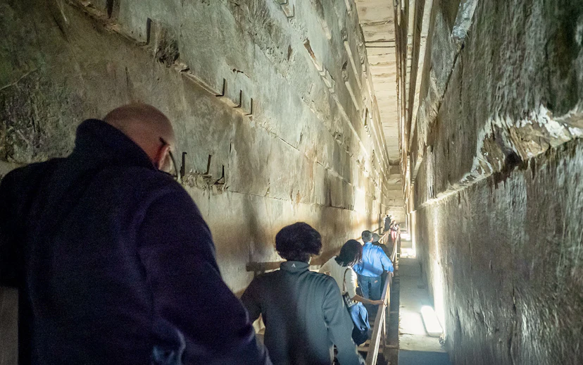 Visitors walking through a narrow passage inside Khufu's Great Pyramid.