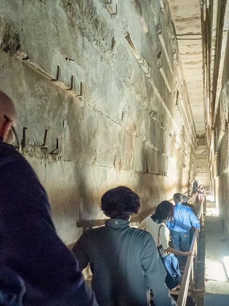 Visitors walking through a narrow passage inside Khufu's Great Pyramid.
