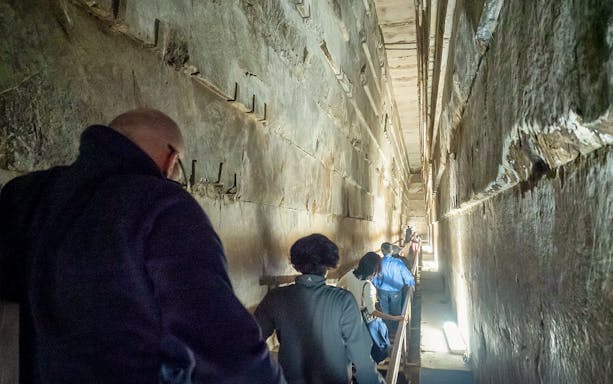 Visitors walking through a narrow passage inside Khufu's Great Pyramid.