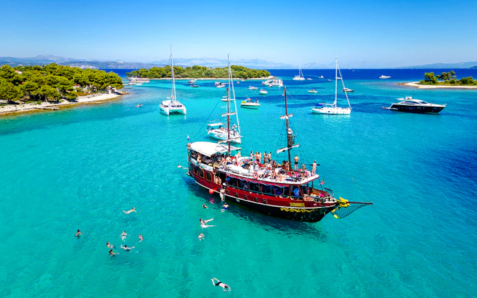 Tourists swimming near a boat in Blue Lagoon, Croatia.