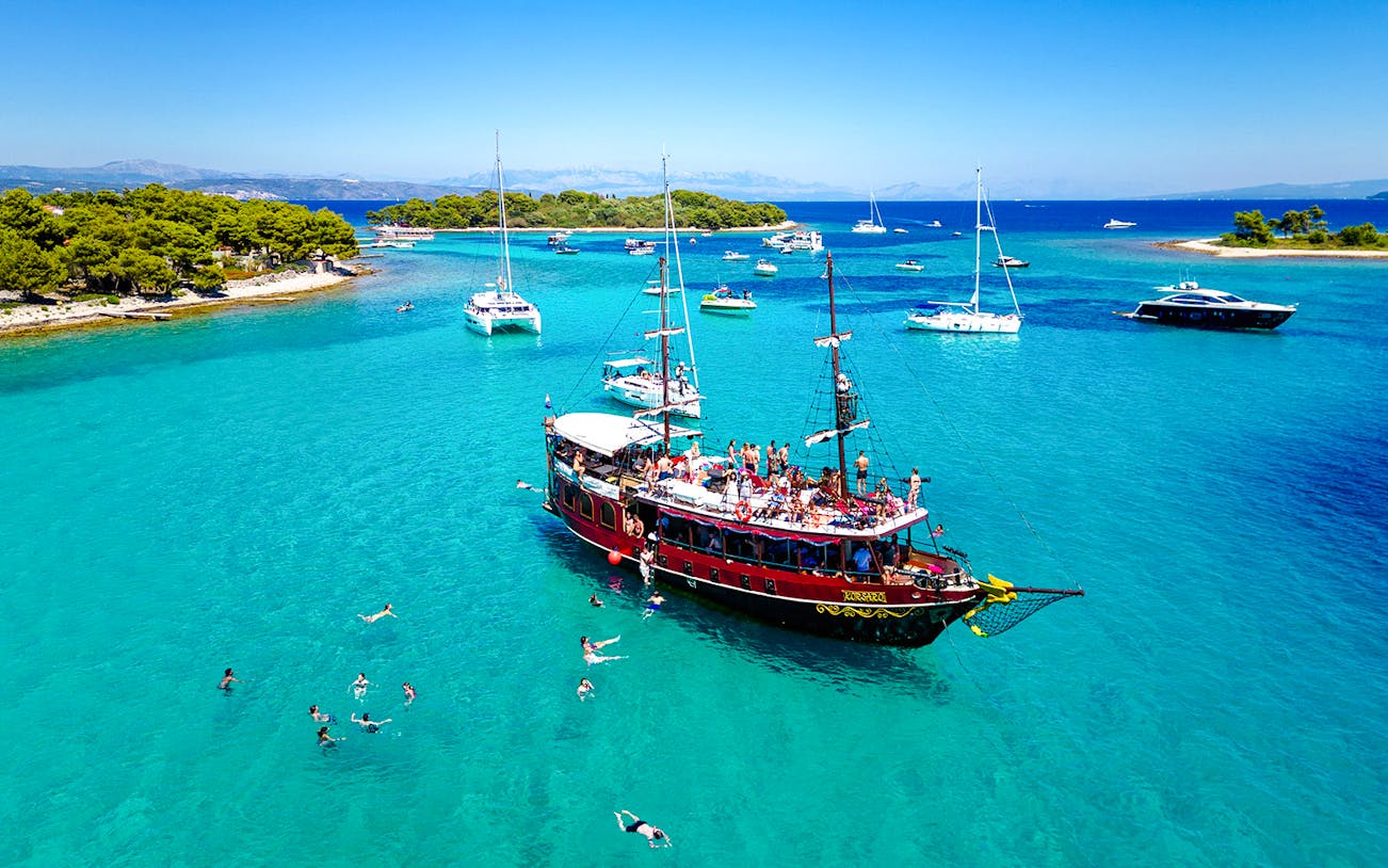 Tourists swimming near a boat in Blue Lagoon, Croatia.