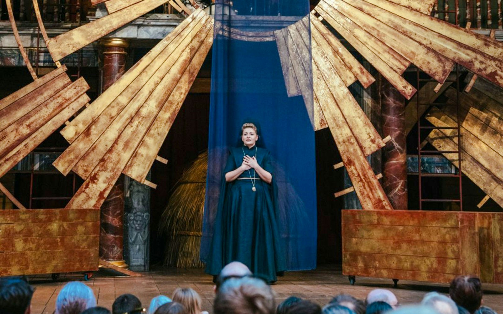 Performer on stage during Twelfth Night, or What You Will, with golden set design.