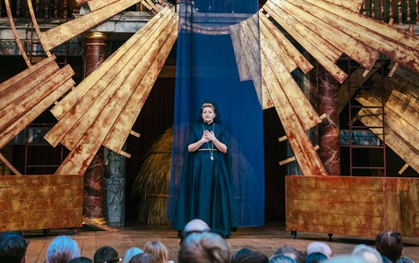 Performer on stage during Twelfth Night, or What You Will, with golden set design.