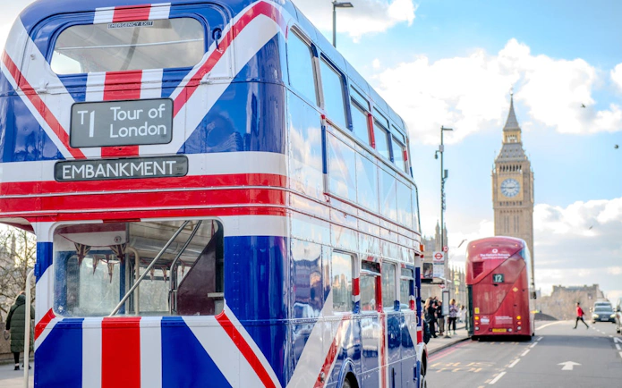 Double-decker bus with Union Jack design near Big Ben, Central London afternoon tea tour.