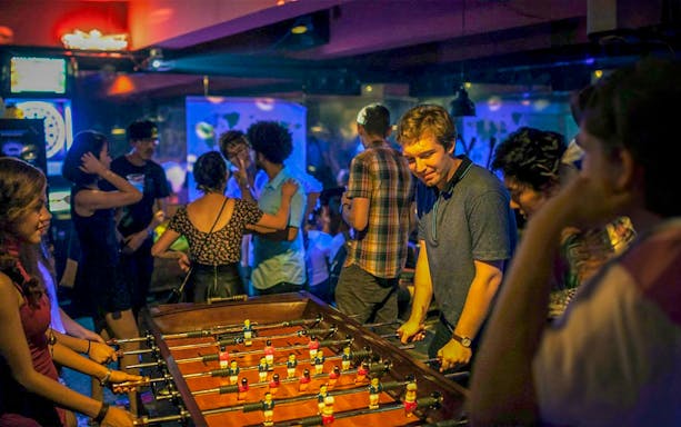 People playing foosball in a lively Seoul pub during a pub crawl.