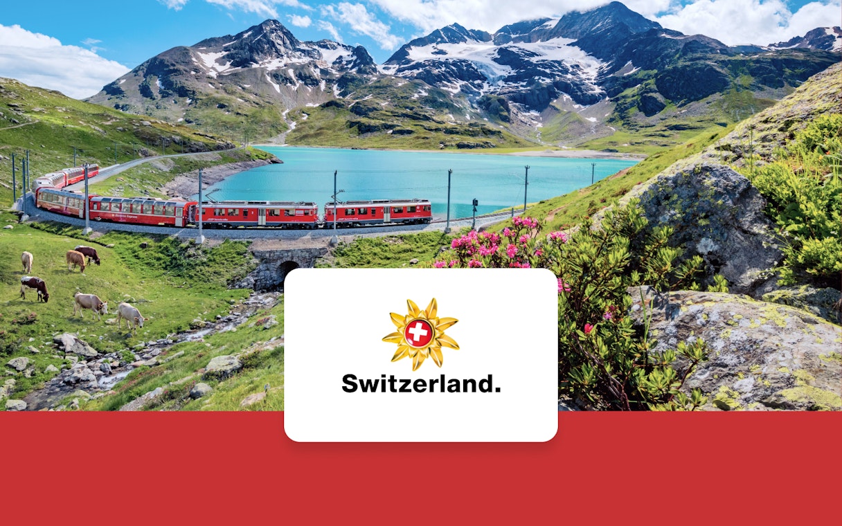 Train traveling through Swiss Alps near a turquoise lake with mountains in the background.