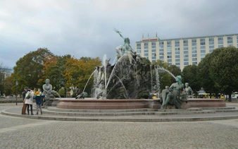 Neptune Fountain in Berlin with statues and tourists nearby.