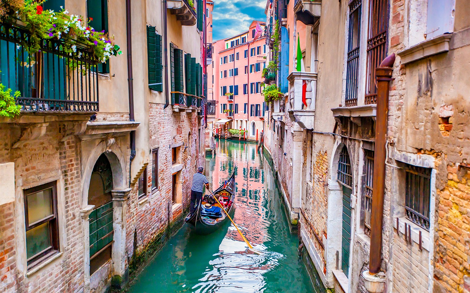 Gondola navigating a narrow canal in Venice, Italy, with historic buildings on either side.