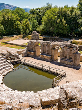 Ancient amphitheater ruins surrounded by trees in Butrint National Park, Albania.