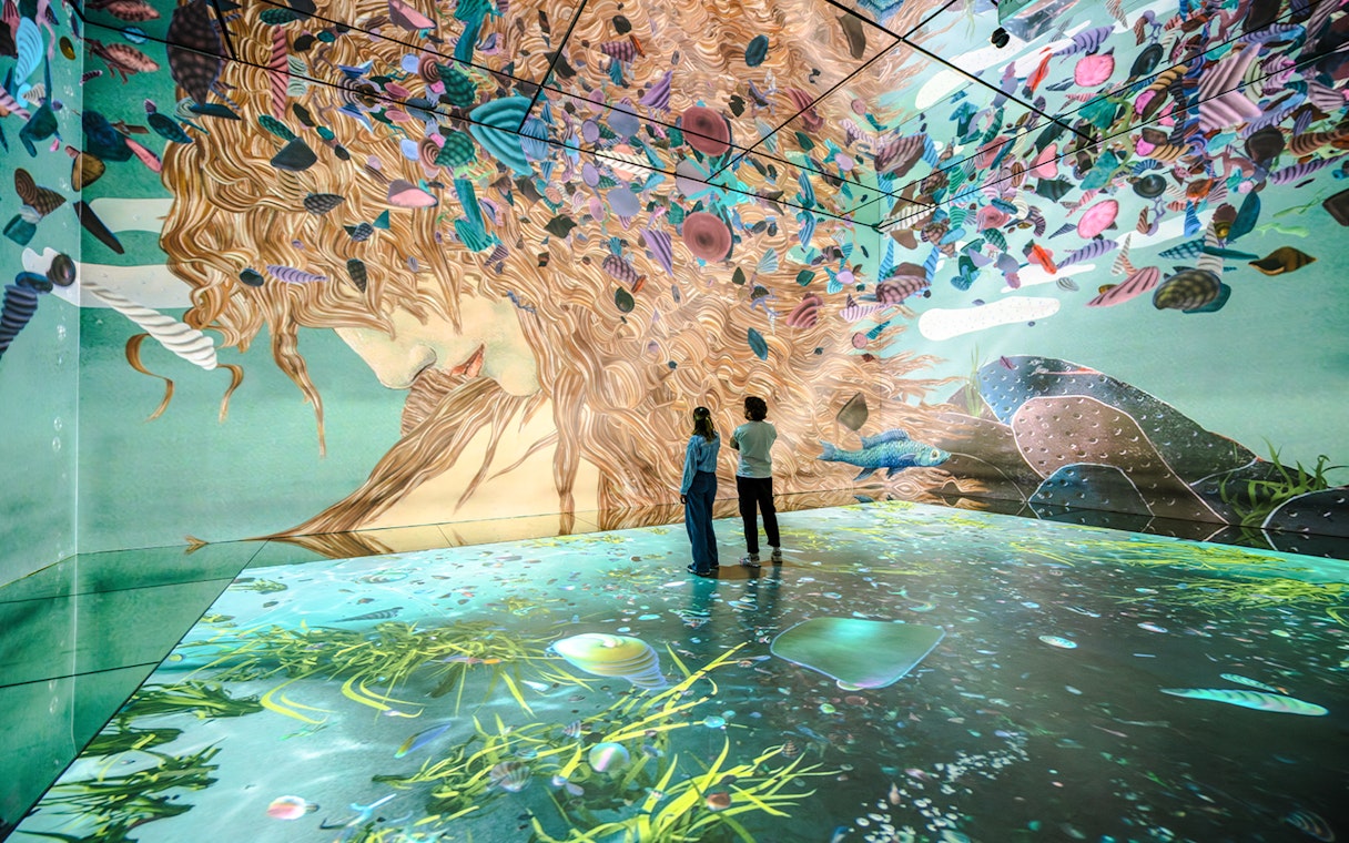 Visitors exploring immersive art projections at Frameless London exhibit.