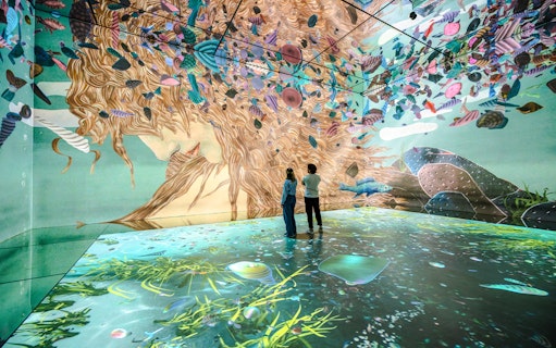 Visitors exploring immersive art projections at Frameless London exhibit.