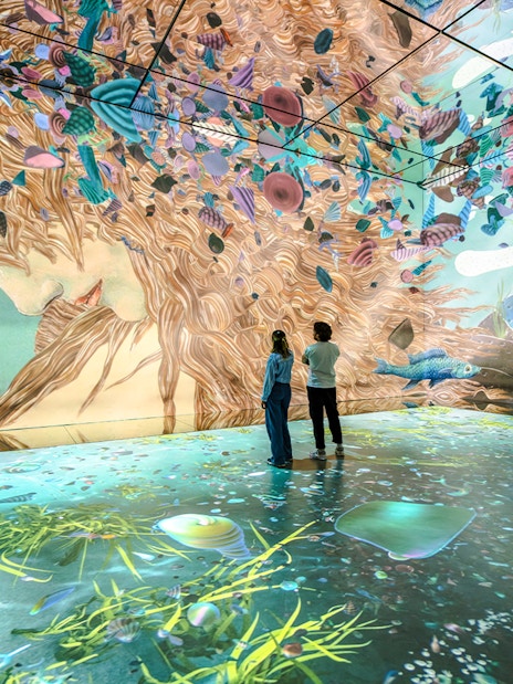 Visitors exploring immersive art projections at Frameless London exhibit.