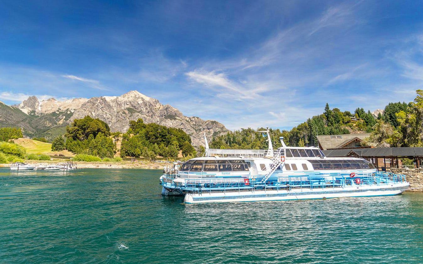 Excursion boat docking at Puerto Blest on Nahuel Huapi Lake with mountains in the background.