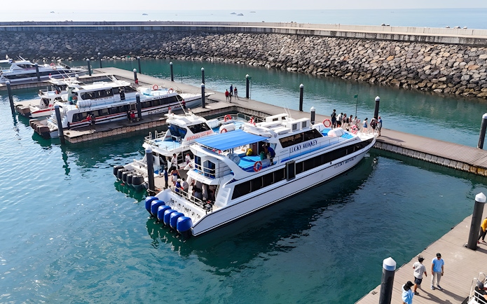 Boats docked at the pier near Nusa Penida with passengers boarding.