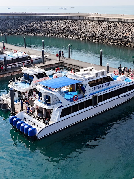 Boats docked at the pier near Nusa Penida with passengers boarding.