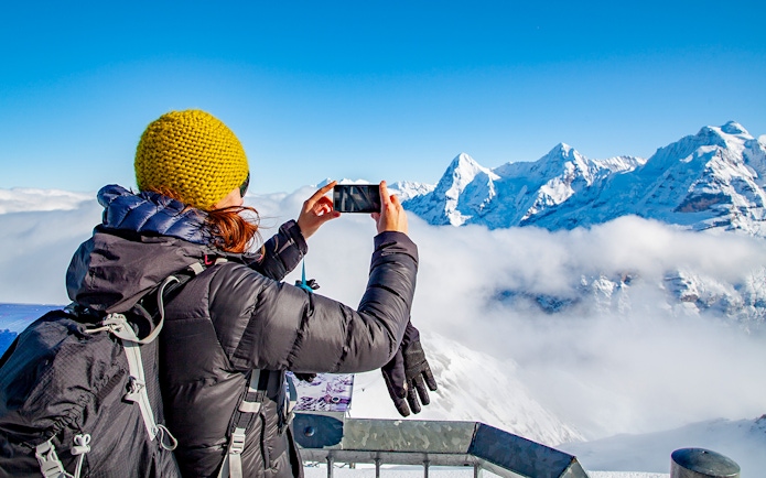 Traveler photographing snowy peaks in Grindelwald, Switzerland.