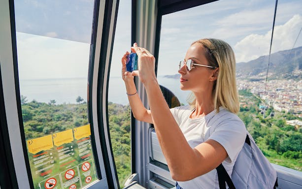 Woman taking photos inside a cable car overlooking Spanish landscape.