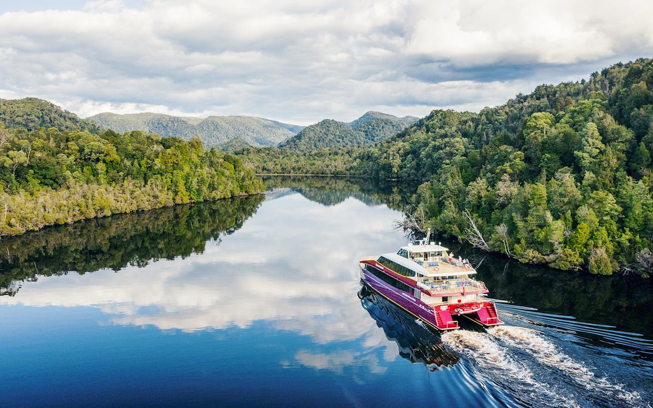 Cruise boat on Gordon River surrounded by lush forest, Strahan, Tasmania.