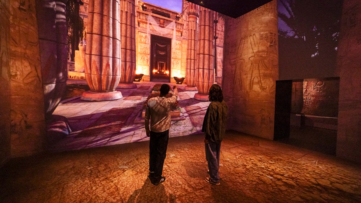 Visitors viewing ancient Egyptian temple projection at Fabrique des Lumières exhibition.