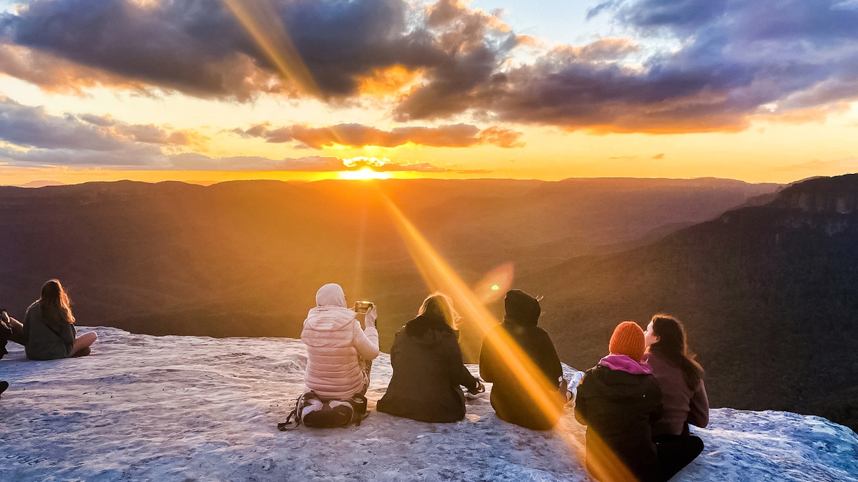 Tourists enjoying Jamison Valley sunset views on Blue Mountains day trip from Sydney.