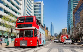 Turistik Hop-On Hop-Off bus on a street in Santiago, Chile with city skyline.