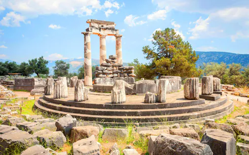 Ancient ruins of the Tholos of Delphi with surrounding landscape in Greece.