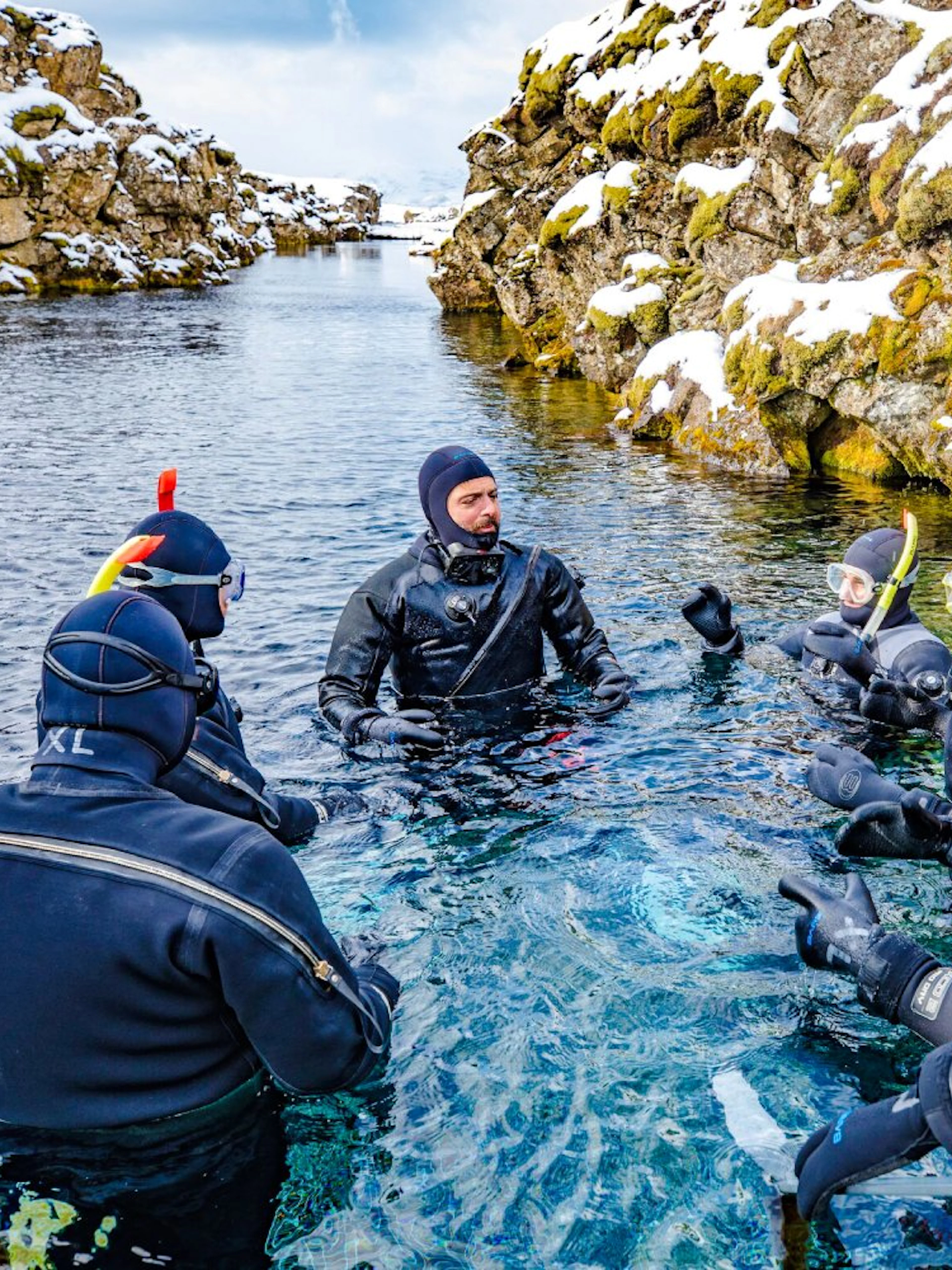 Instructor briefing snorkelers in wetsuits at Silfra fissure, Iceland.
