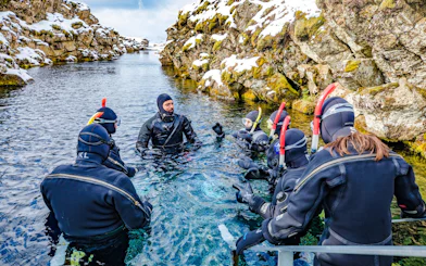 Instructor briefing snorkelers in wetsuits at Silfra fissure, Iceland.