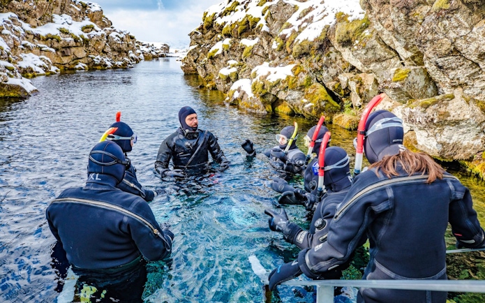 Instructor briefing snorkelers in wetsuits at Silfra fissure, Iceland.