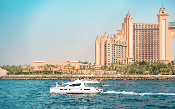 Luxury yacht cruising past Atlantis The Palm, Dubai.
