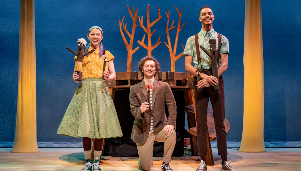 Performers on stage during Stick Man show, West End, with tree props in background.