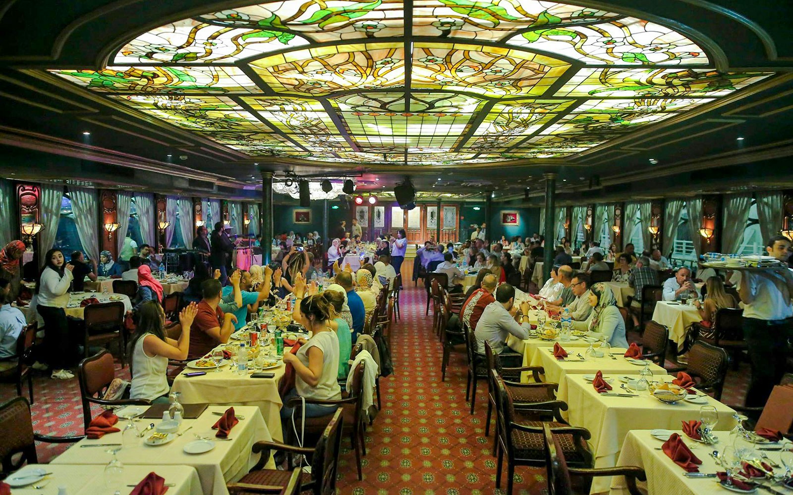 Guests dining at a luxury Nile dinner cruise with stained glass ceiling.