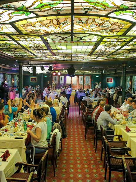 Guests dining at a luxury Nile dinner cruise with stained glass ceiling.