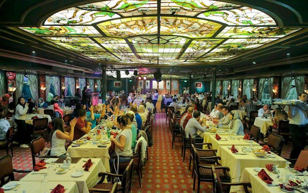 Guests dining at a luxury Nile dinner cruise with stained glass ceiling.