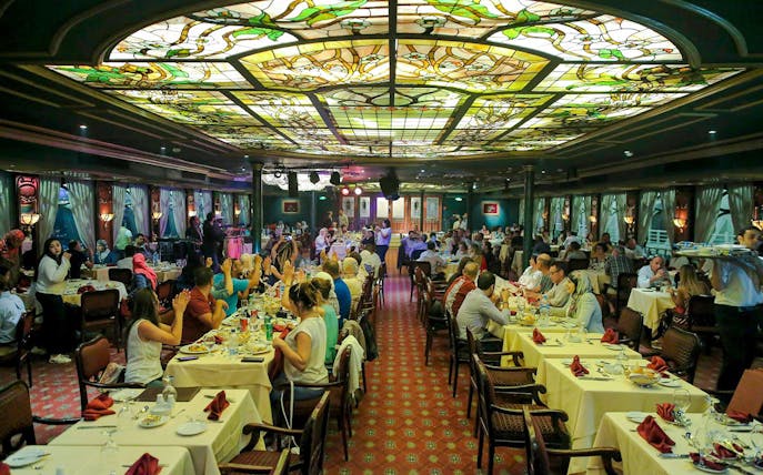 Guests dining at a luxury Nile dinner cruise with stained glass ceiling.