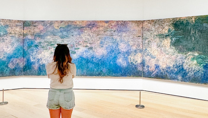 Woman viewing Monet's Water Lilies painting at a museum in Paris, France.