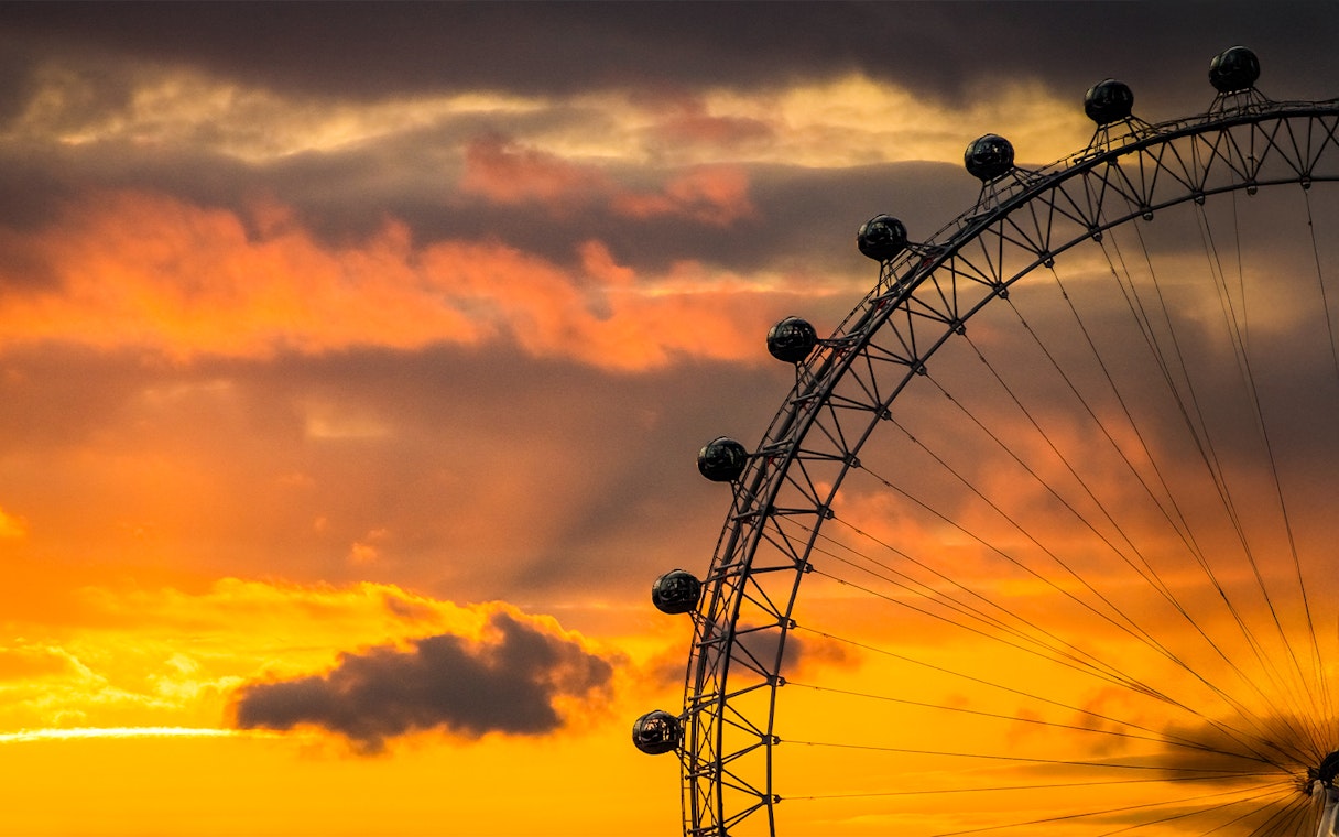 London Eye silhouetted against a vibrant sunset sky.