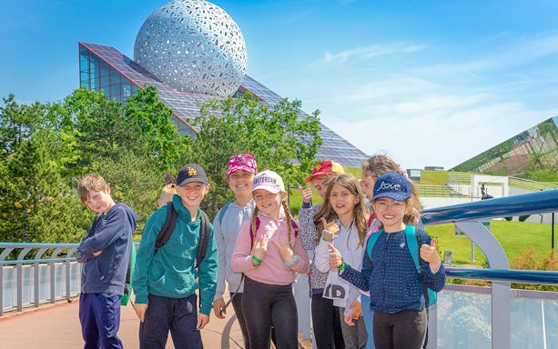 Group of children smiling in front of Futuroscope's architectural dome in France.