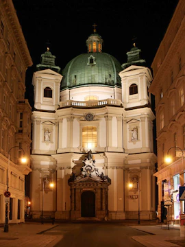 Saint Peter's Church in Vienna illuminated at night with baroque architecture.