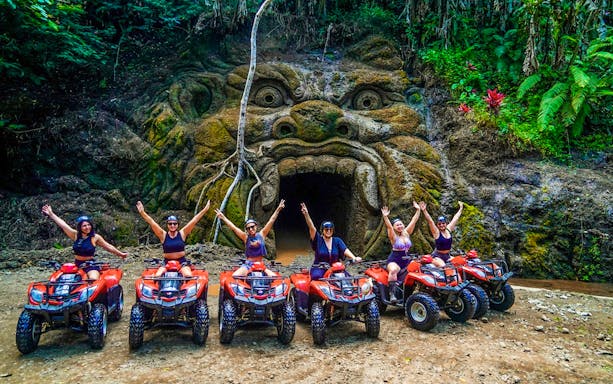 ATV riders in front of Gorilla Face cave entrance in Ubud jungle.