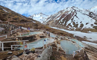 Hot springs at Termas Baños Colina with snow-capped Andes in Cajon del Maipo, Santiago.