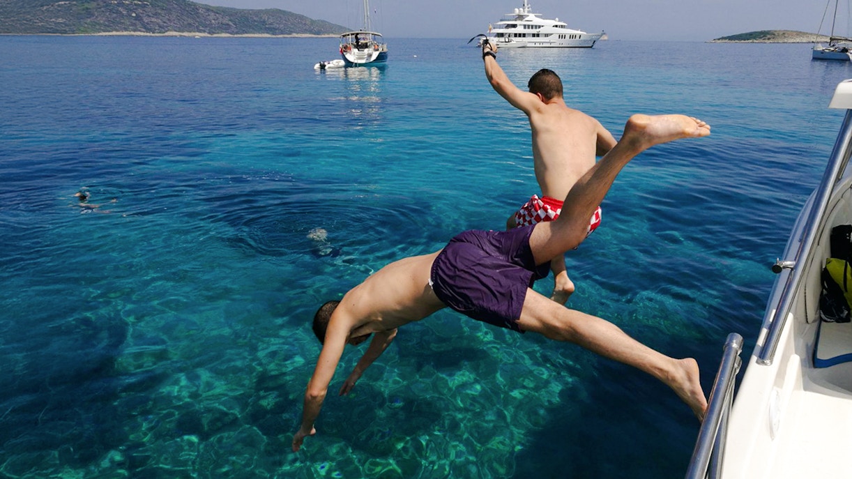 Aerial view of Komiza town with red-roofed buildings and boats in Vis, Croatia.