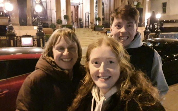 Group of people smiling in front of a historic building in Belfast at night.