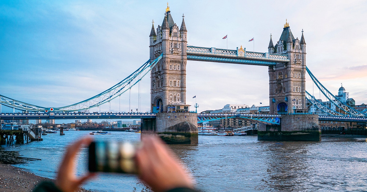 Tower Bridge in London with person photographing from riverbank.