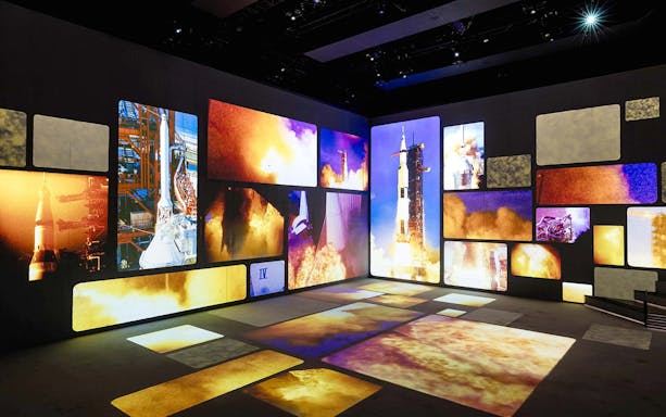 Multimedia display of rocket launches and space exploration, part of The Moonwalkers exhibit.