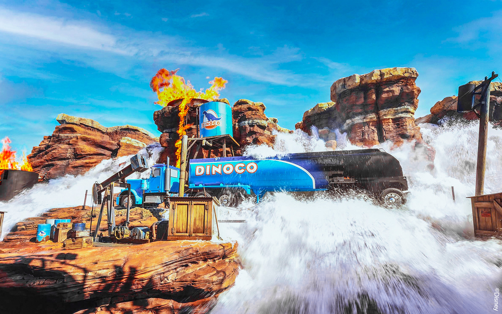 Disneyland Paris Cars attraction with Dinoco truck amidst water and fire effects.