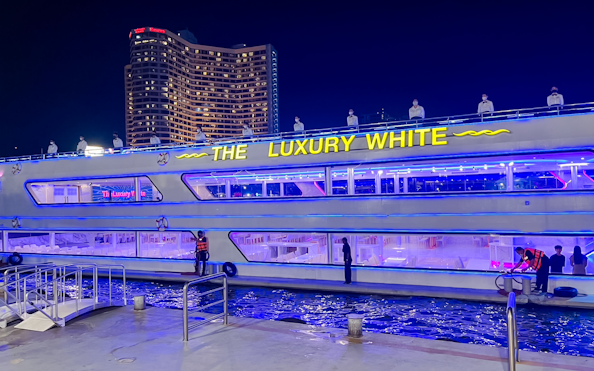 Luxury White Dinner Cruise docked at ICONSIAM, Bangkok, with illuminated decks and city skyline.