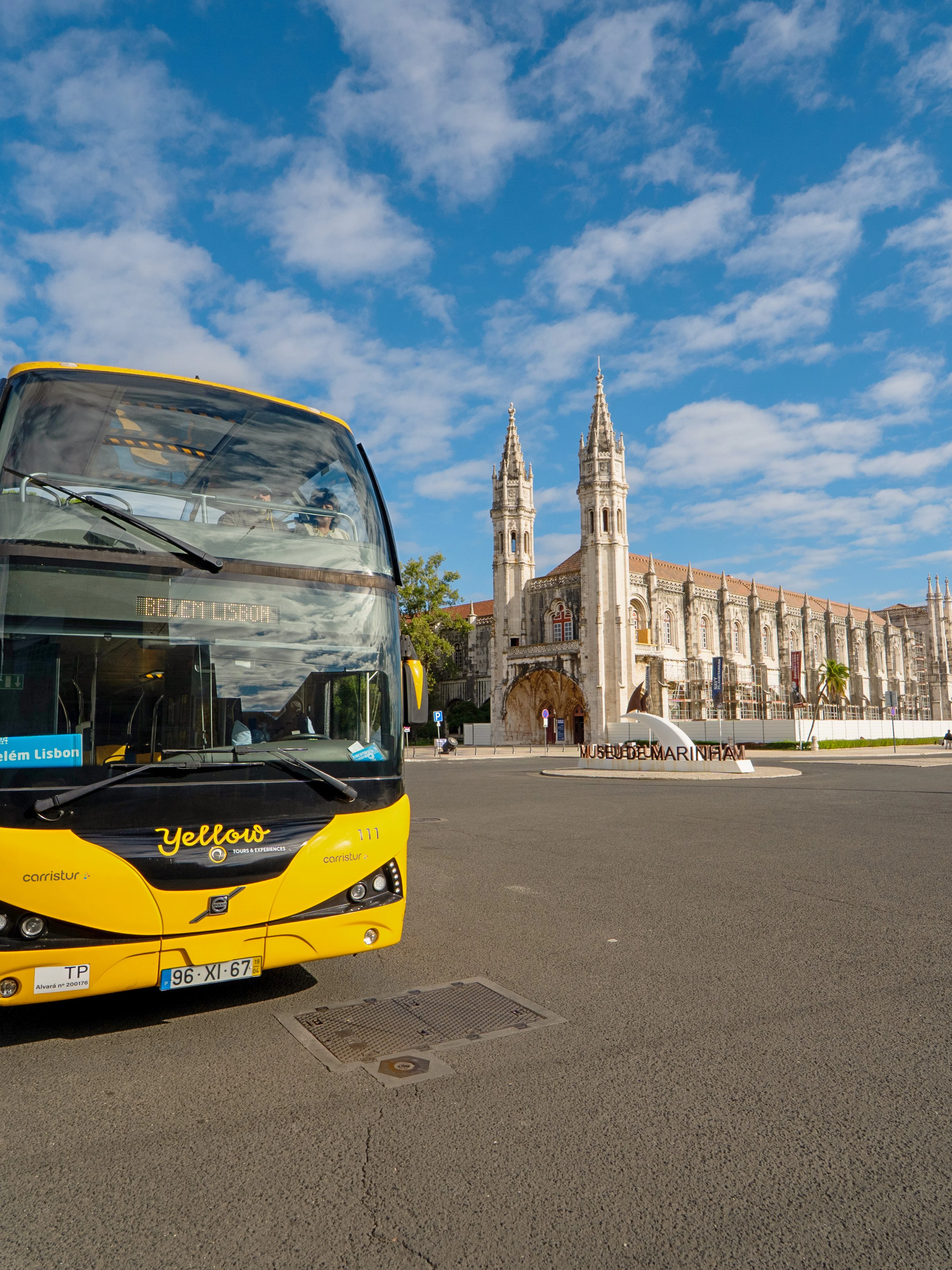 Yellow bus in front of Jerónimos Monastery during Lisbon Hop-on Hop-off tour.